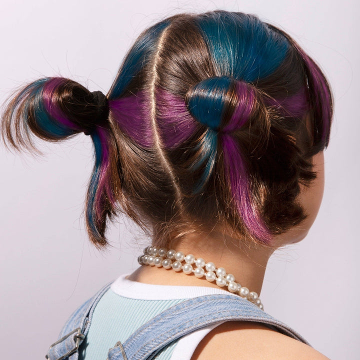 Blue and purple temporary hair chalk streaked through hair styled in space buns