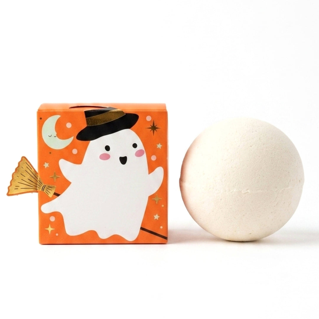 Cream bath bomb beside orange box with a smiling ghost in a witch hat, a sweet Halloween party favor for kids