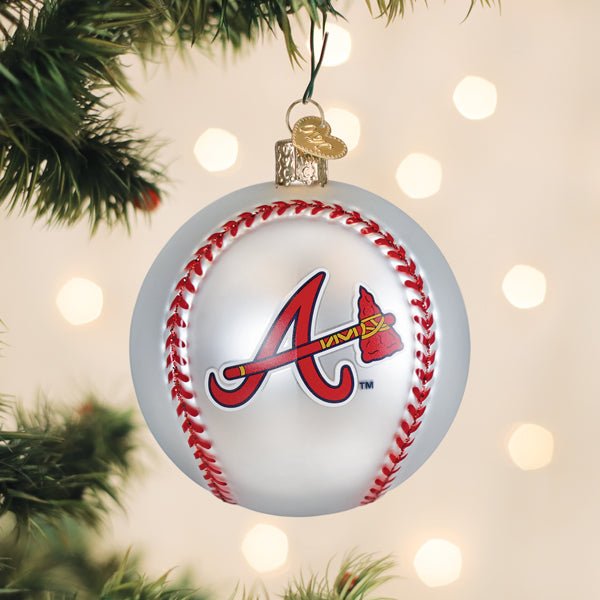 Braves baseball ornament hanging on a lit Christmas tree with warm bokeh lights and pine branches