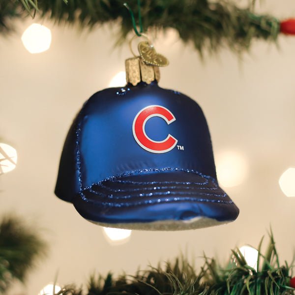 Cubs cap ornament hanging on a lit Christmas tree with warm glowing bokeh lights behind