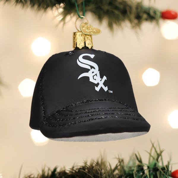 White Sox cap ornament hanging on a lit Christmas tree with warm glowing bokeh lights behind