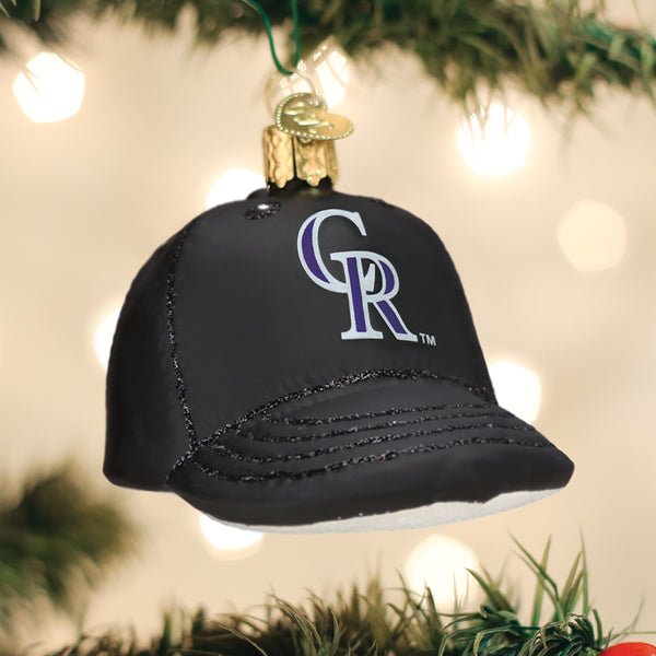 Colorado Rockies cap ornament hanging on a lit Christmas tree with warm bokeh lights and pine branches