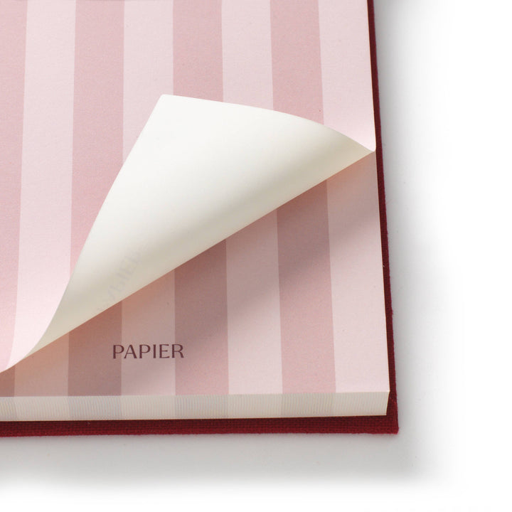 Sheet lifted on the Bloom notepad to show the pink stripe print and thick sheet stack, smooth paper for daily lists
