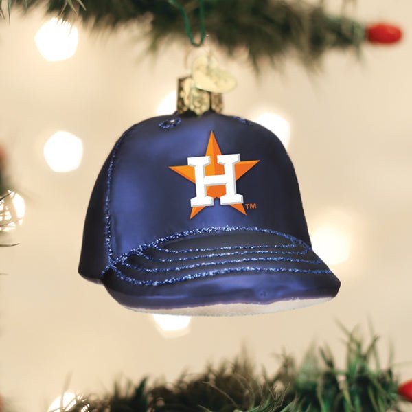 Houston Astros cap ornament hanging on a lit Christmas tree with warm bokeh lights and pine branches