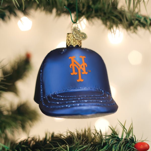 Mets cap ornament hanging on a lit Christmas tree with warm glowing bokeh lights behind