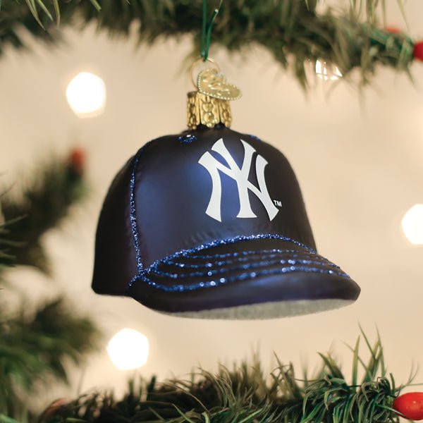 Yankees cap ornament hanging on a lit Christmas tree with warm glowing bokeh lights behind