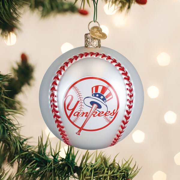 New York Yankees baseball ornament hanging on a lit Christmas tree with warm bokeh lights and pine branches