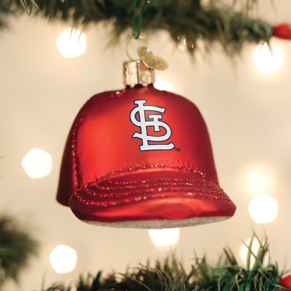 Cardinals cap ornament hanging on a lit Christmas tree with warm glowing bokeh lights behind