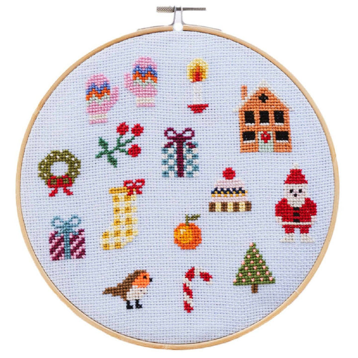 Colorful Christmas cross stitch sampler hoop with festive motifs on light blue fabric