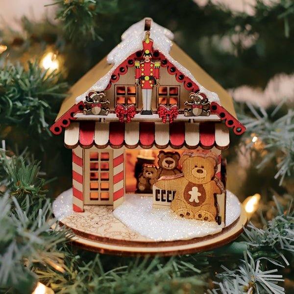 Teddy bear toy shop cottage ornament glowing from inside on a lit Christmas tree