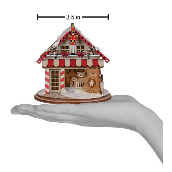 Teddy bear shop cottage ornament on an open palm beneath a 3.5 inch width marker