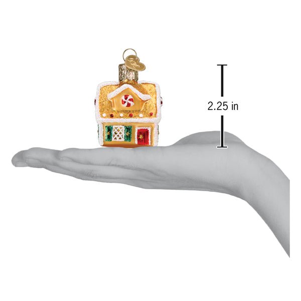 Mini gingerbread house ornament on an open palm beside a 2.25 inch height marker