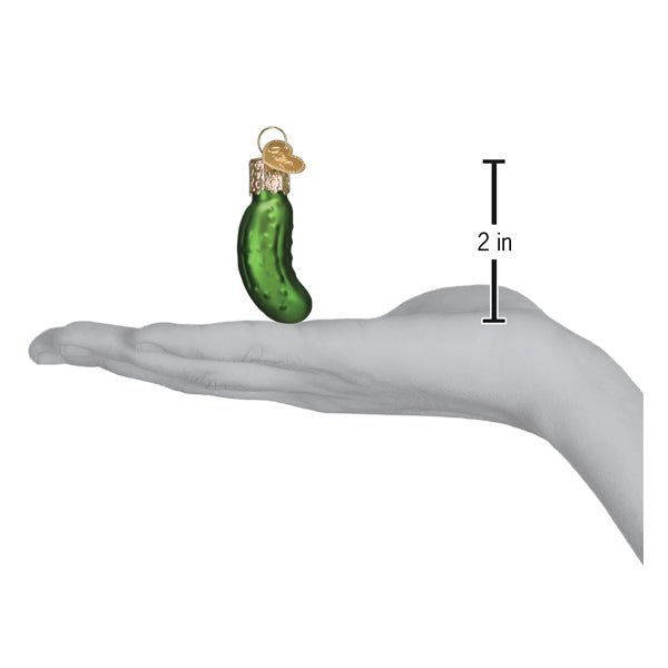 Mini pickle ornament on an open palm beside a 2 inch height marker