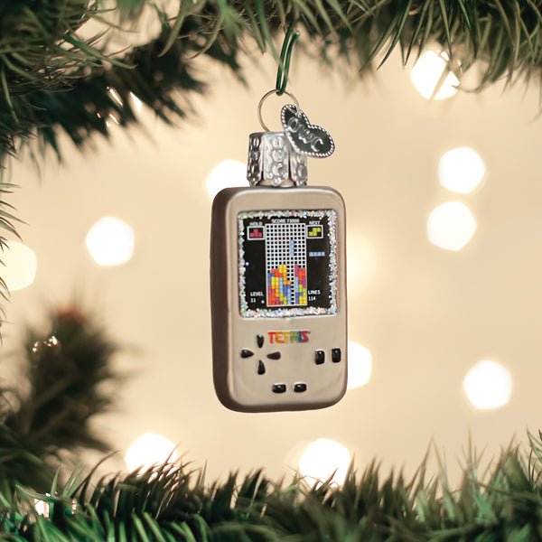 Silver Tetris handheld ornament hanging on a lit Christmas tree with warm bokeh lights