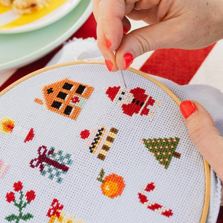 Stitching a Santa motif on the colorful Christmas cross stitch sampler
