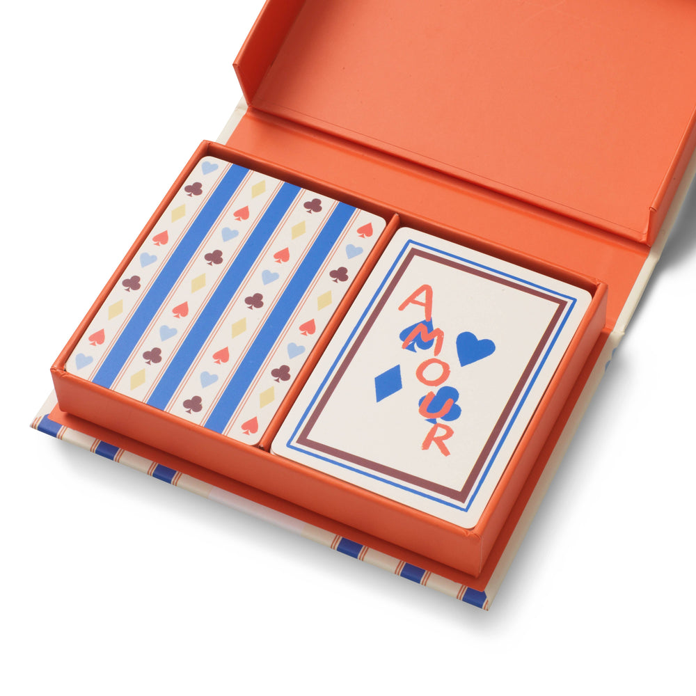 Open keepsake box showing two Papier playing card decks, one striped and one cream Amour design, for holiday game nights