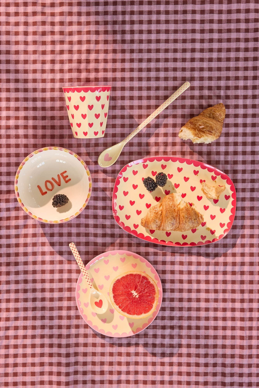 Favorite Hearts plate with a heart cup, LOVE bowl, croissant, berries, and grapefruit on purple gingham