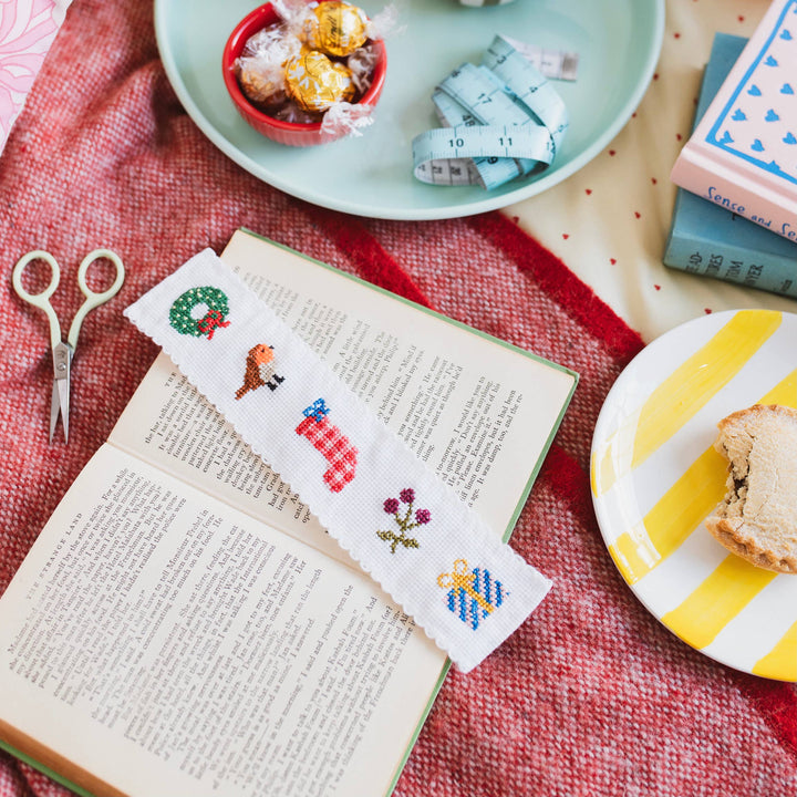 Christmas bookmark cross stitch on an open book with mince pie and tape measure