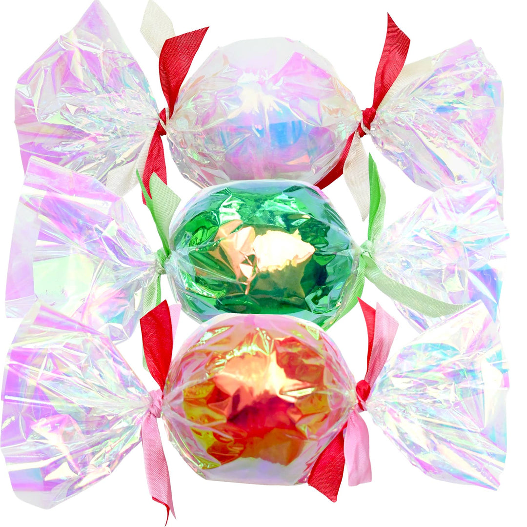 Three iridescent bon bon surprise balls in pearl, green, and copper cellophane tied with holiday ribbons