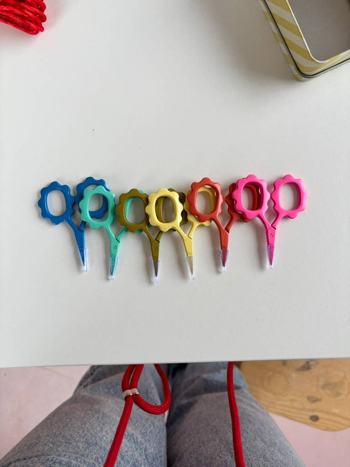 Row of colorful sunflower embroidery scissors in blue, mint, olive, yellow, and pink