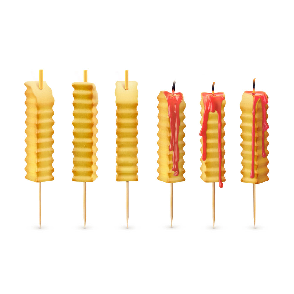 Six french fry birthday candles on white background, three unlit and three lit with red ketchup wax dripping down the sides