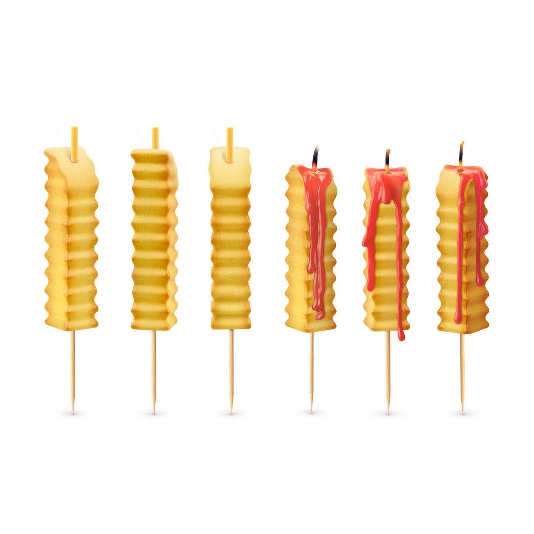 Six french fry birthday candles on white background, three unlit and three lit with red ketchup wax dripping down the sides