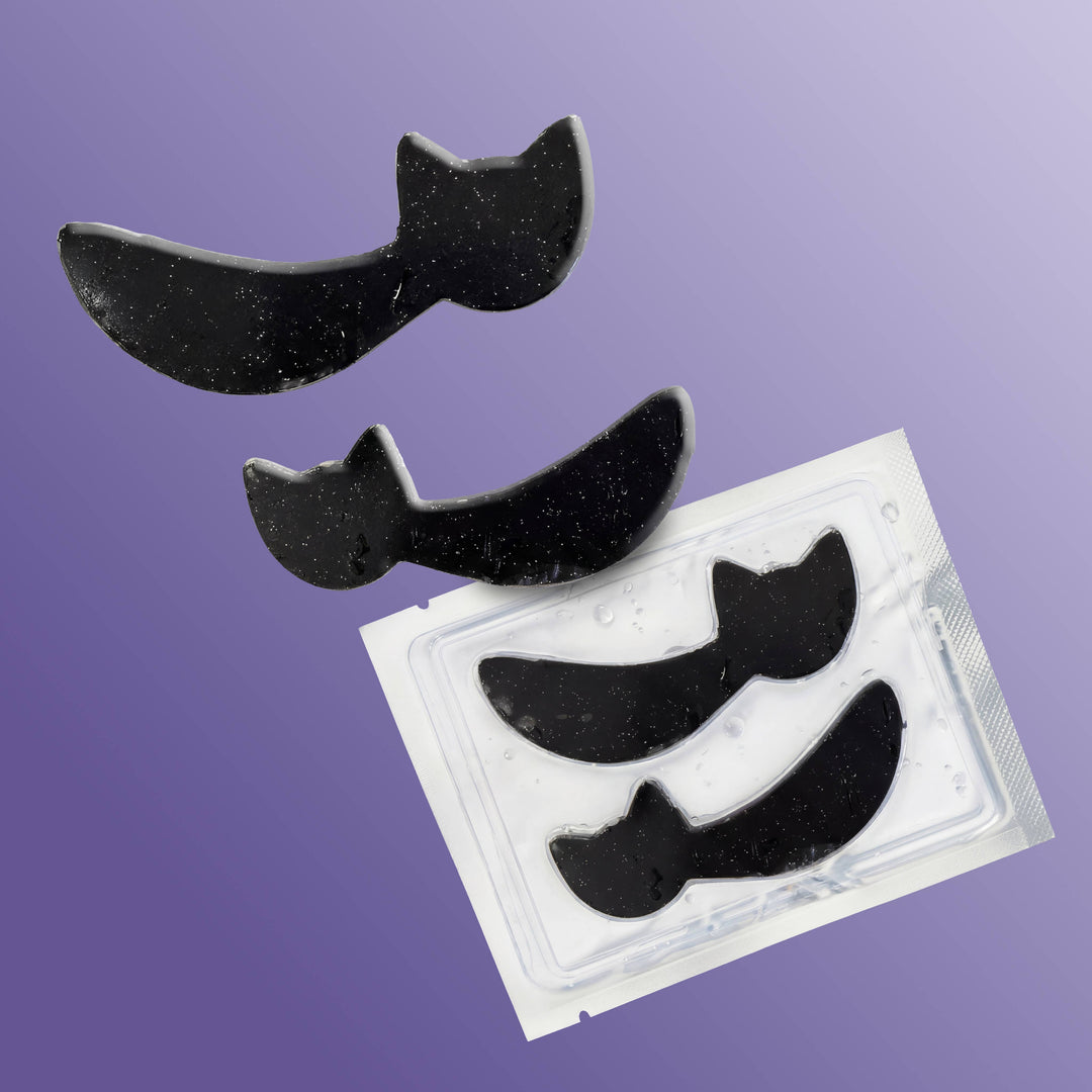 Black cat hydrogel patches tumbling from their clear tray on a purple ombre background, boo basket ready