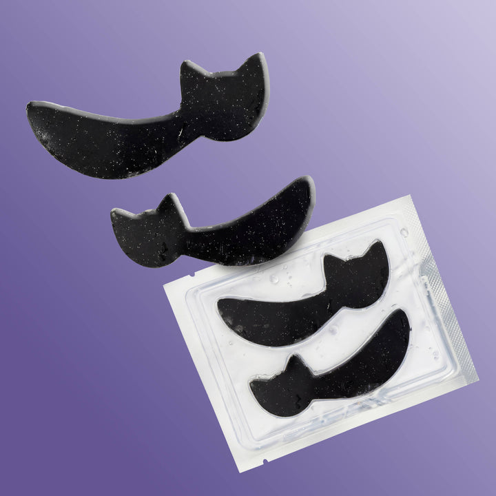 Black cat hydrogel patches tumbling from their clear tray on a purple ombre background, boo basket ready