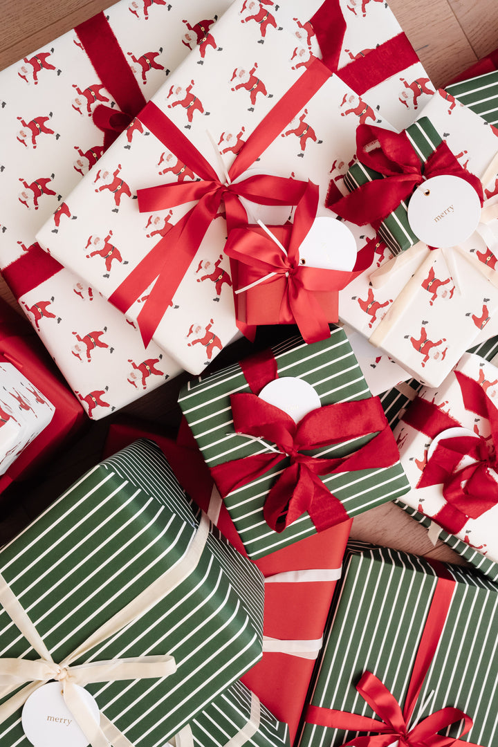 Top-down heap of Santa print and green striped Christmas gifts with frayed red velvet bows