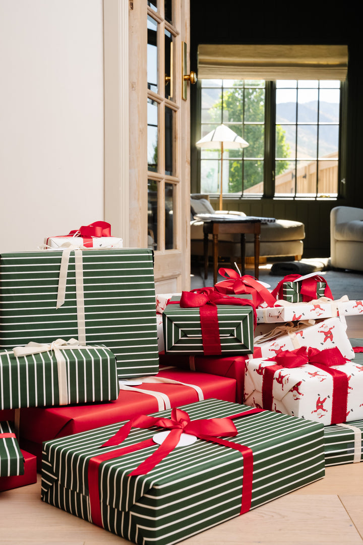 Santa print and green striped presents stacked in a sunlit living room on Christmas morning