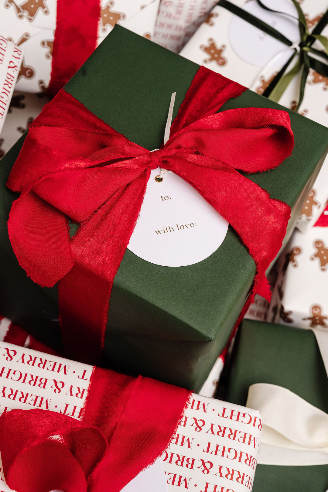 Round to and with love tag on a dark green gift with a frayed red velvet bow