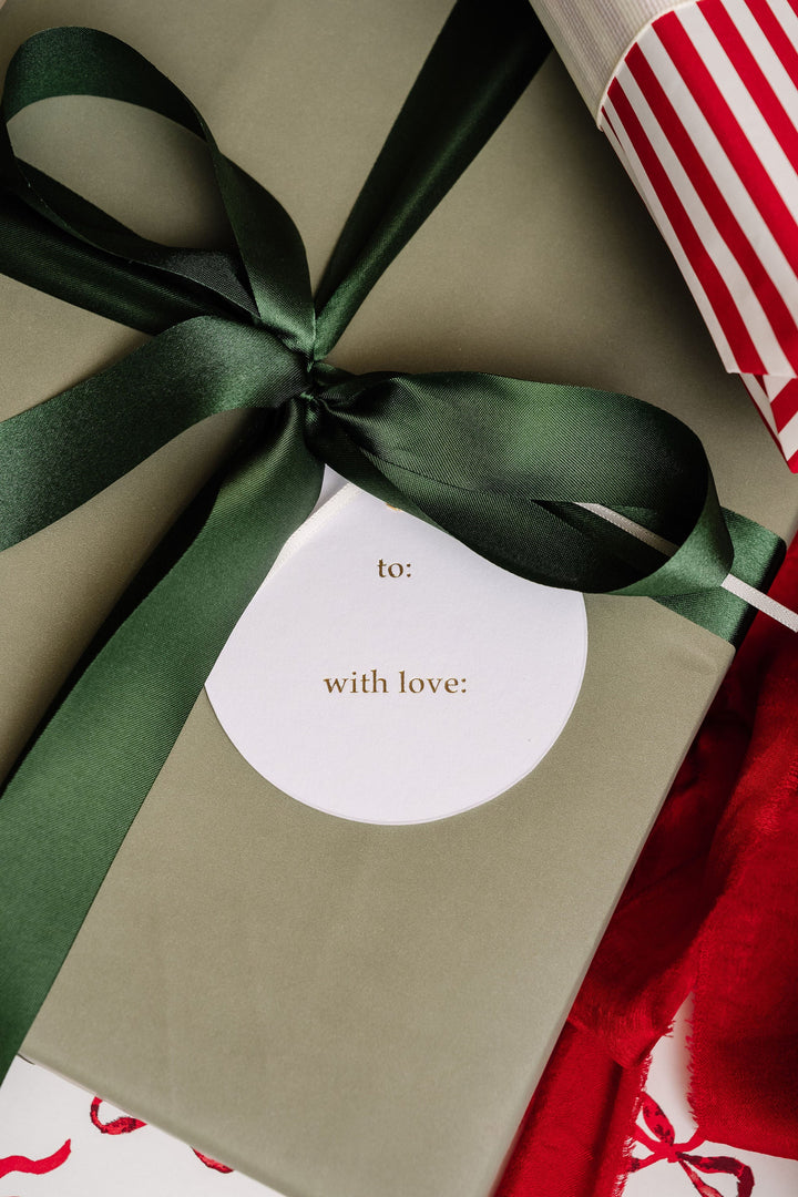 Back of a round to and with love tag under a green satin bow on a soft green gift