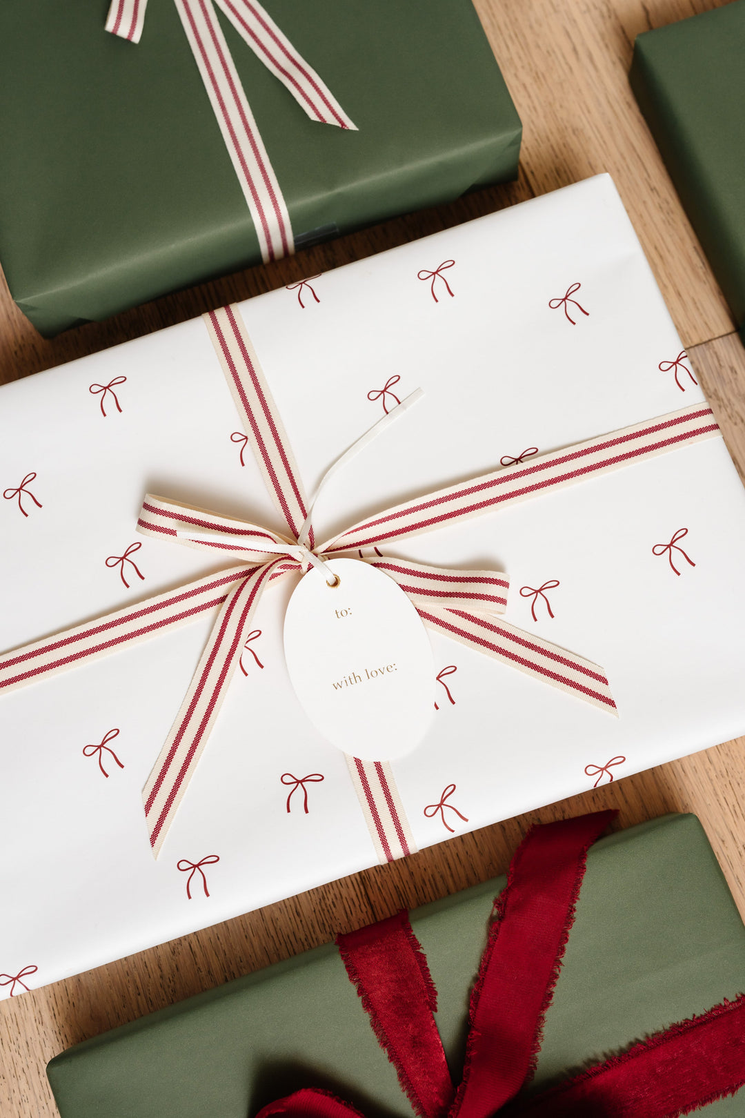 Small red bow print gift wrap with a red and cream striped cotton bow and a gold foil tag