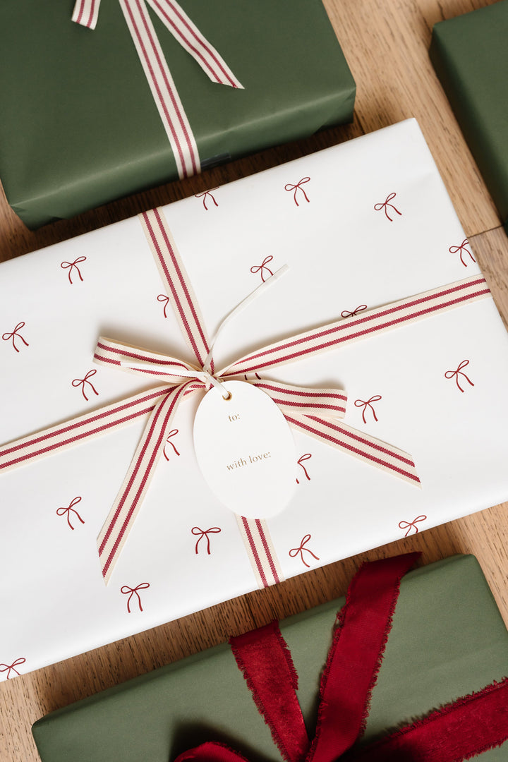 Small red bow print gift wrap with a red and cream striped cotton bow and a gold foil tag