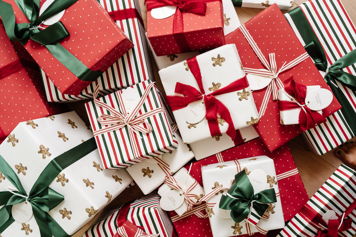 Wide view of Christmas presents in gingerbread, polka dot, and stripe paper with green and red bows