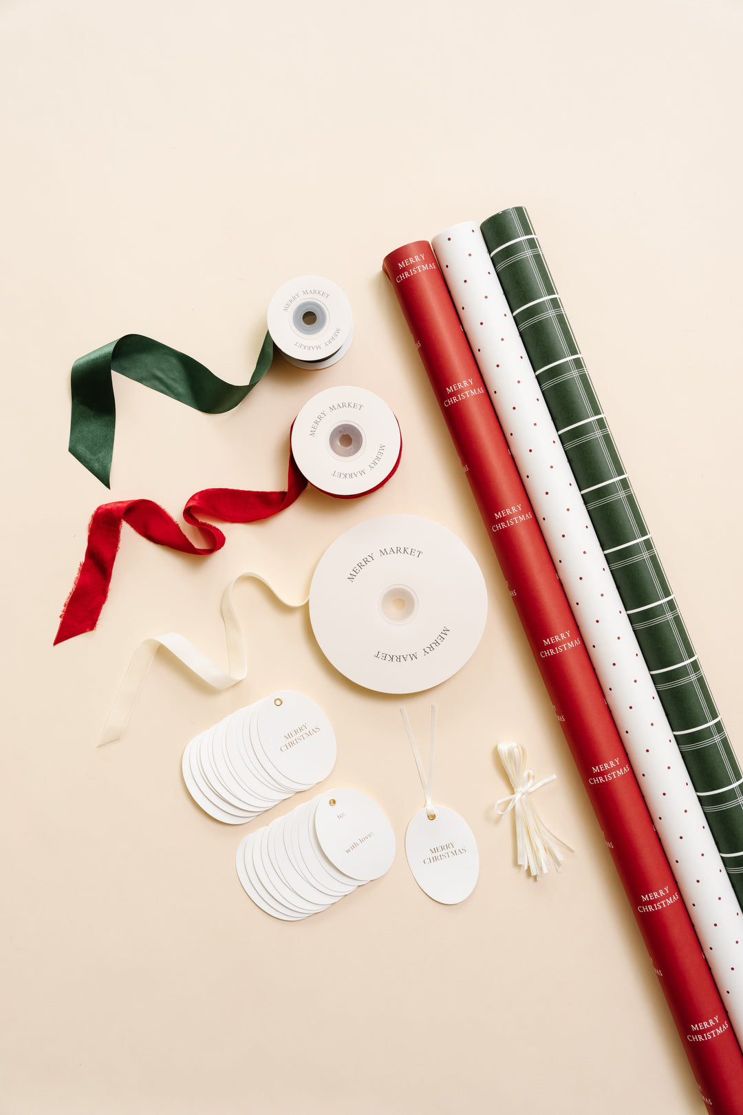 Classic plaid Christmas wrapping paper kit flat lay: three rolls, red velvet, cream velvet, green satin, and oval tags