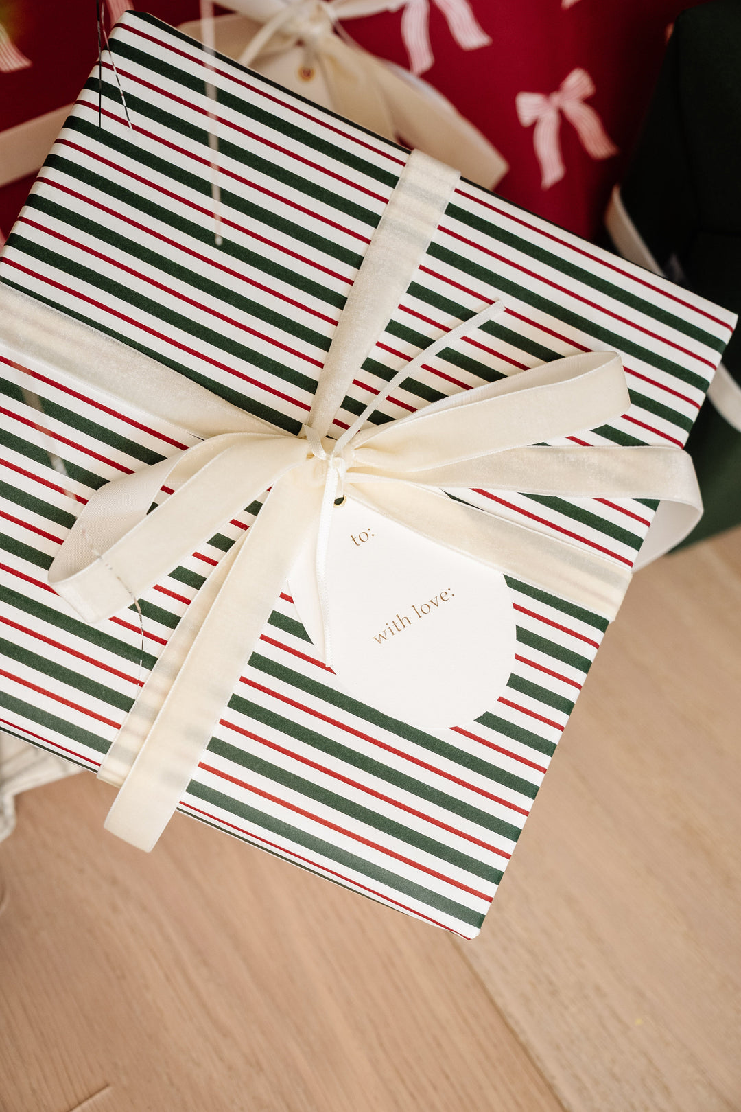 Red and green striped Christmas gift tied with a cream velvet bow and an oval letterpress tag