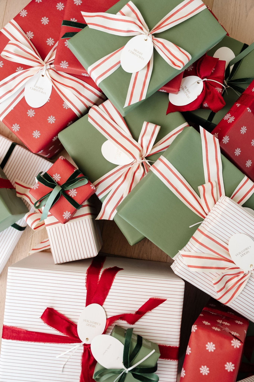 Pile of snowflake, pinstripe, and green Christmas presents tied in red and cream striped ribbon