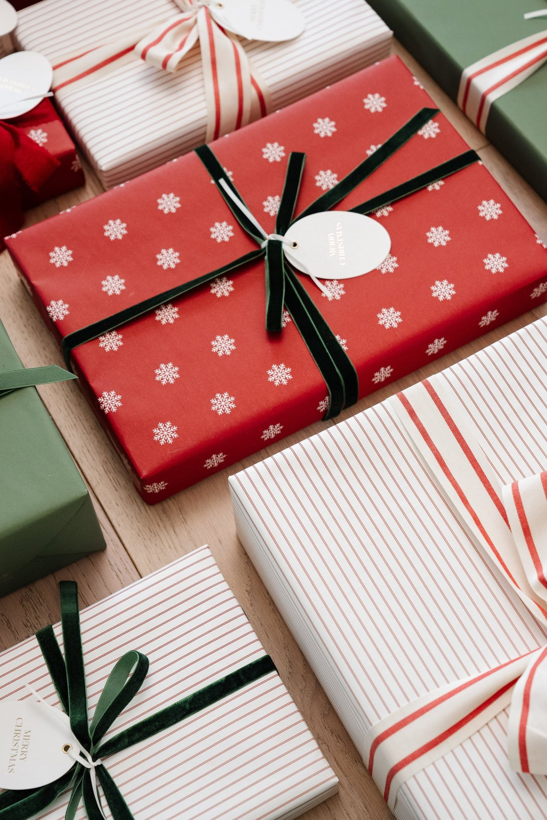 Top-down close-up of red snowflake and pinstripe gifts with green velvet and striped bows