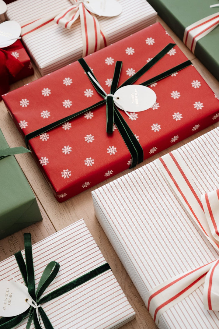 Top-down close-up of red snowflake and pinstripe gifts with green velvet and striped bows