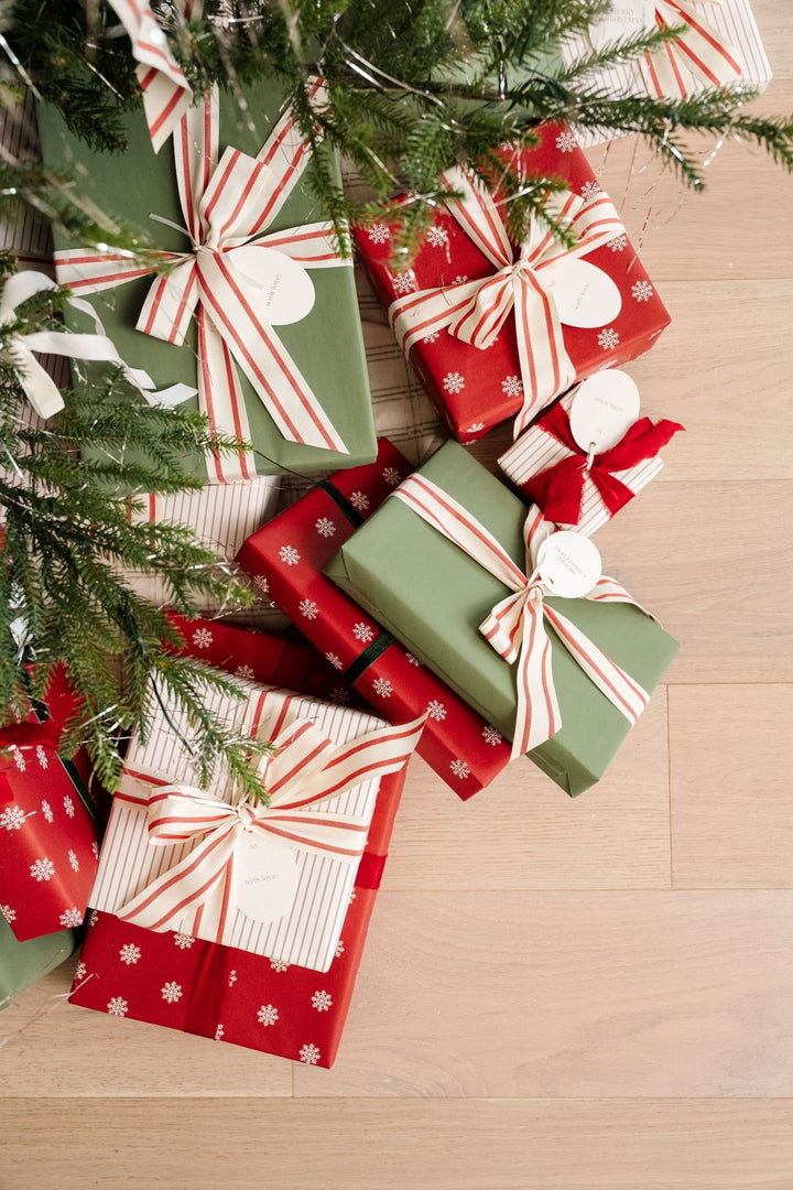 Snowflake and green wrapped gifts with striped bows under Christmas tree branches