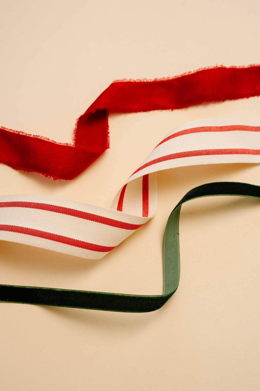 Frayed red velvet, red and cream striped cotton, and green velvet ribbons on cream
