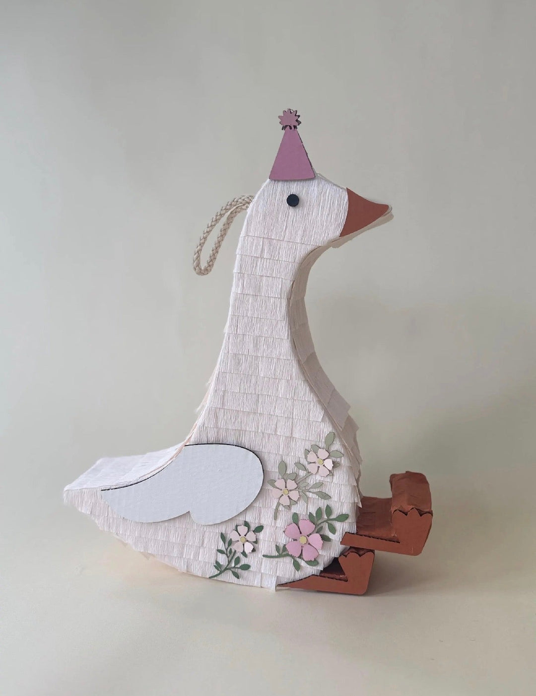 Decorative goose pinata with a purple top hat on a plain background