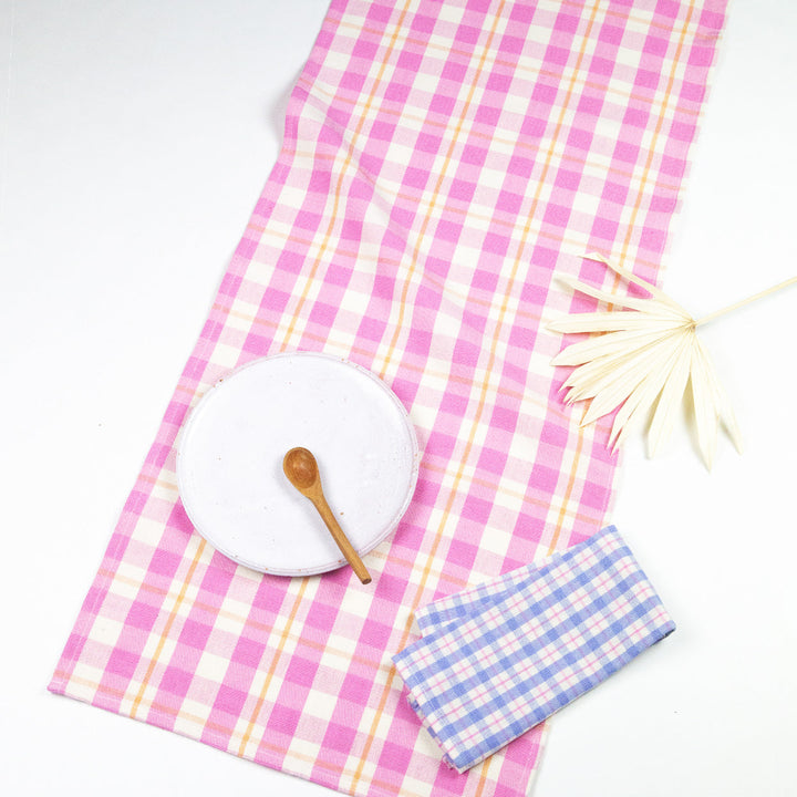 Bubblegum pink and peach plaid table runner laid across a table