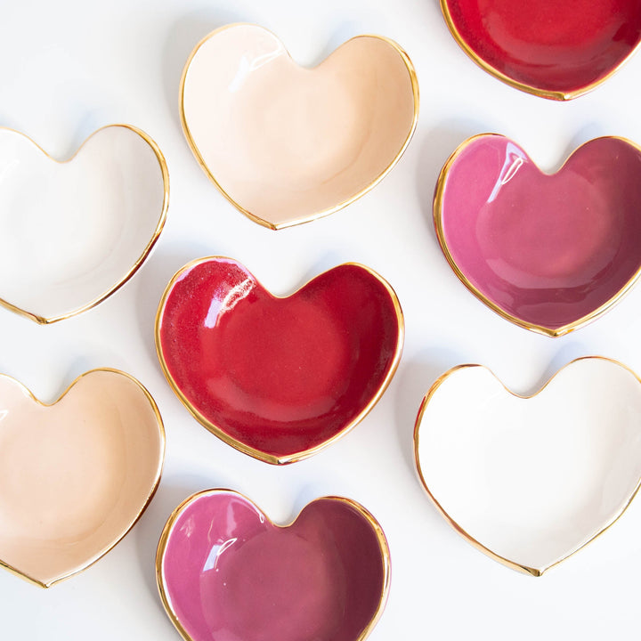 Overhead of heart dishes in peach, berry pink, red, and white with gold rims