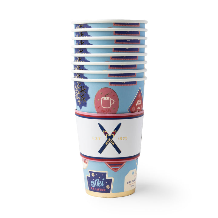 A stack of paper cups with a winter sports design, featuring blue, white, and red colors with ski and snowboard motifs, set against a plain white background.