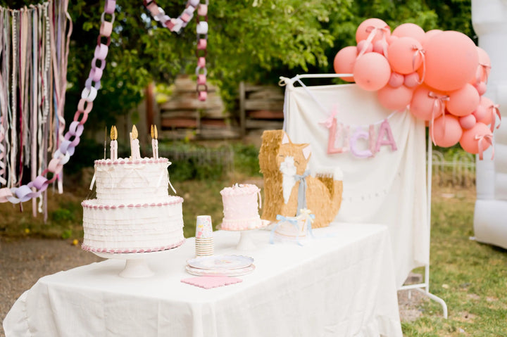 Decorated outdoor birthday party with pinata birthday cake, balloons, and a banner.