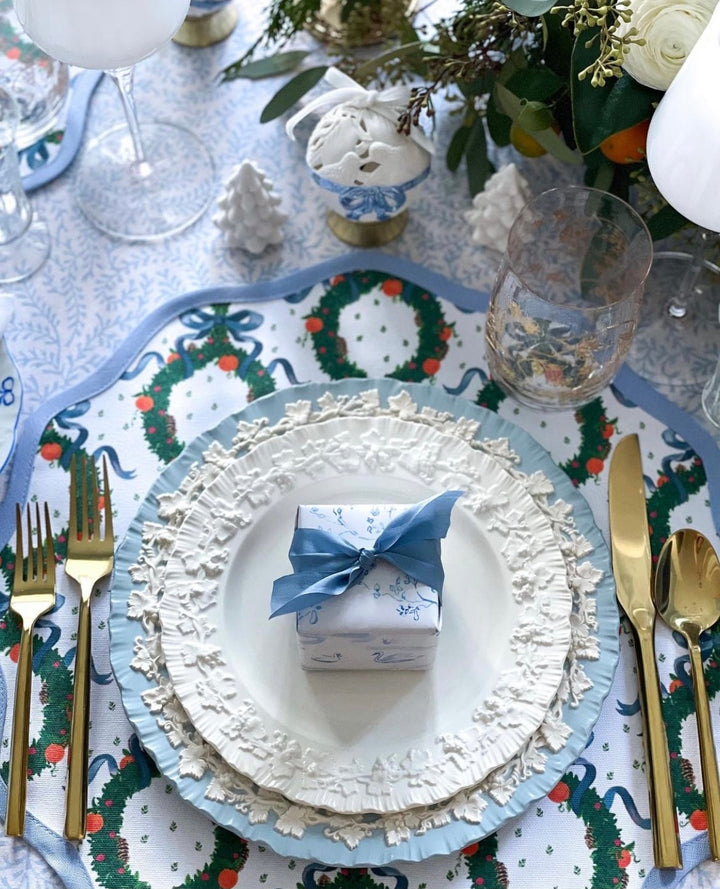 Frances Fields Home holiday placemat, round with a scalloped edge, in a blue Christmas wreath design