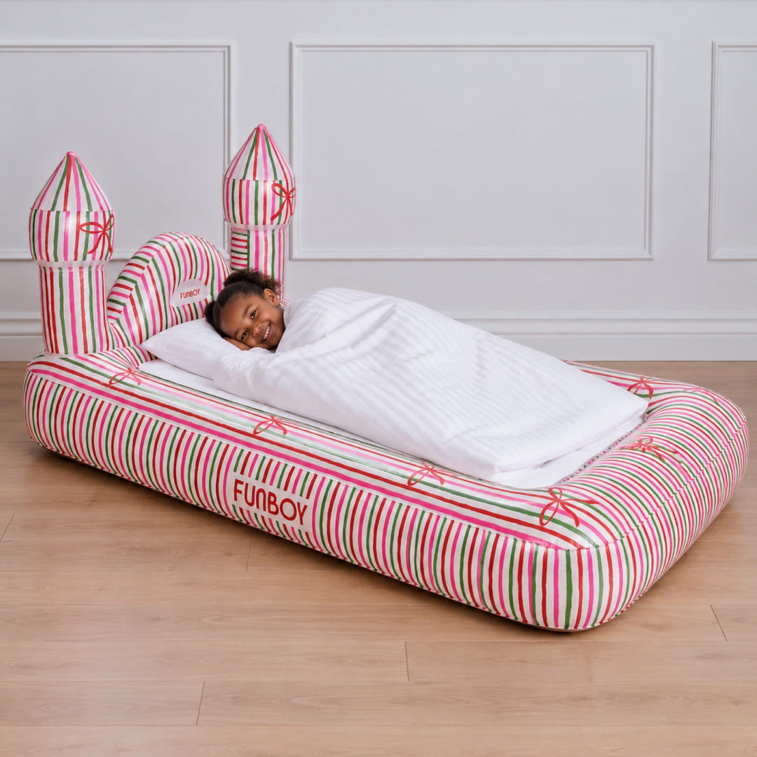 Child asleep in a holiday stripe castle kids air mattress in a white paneled room