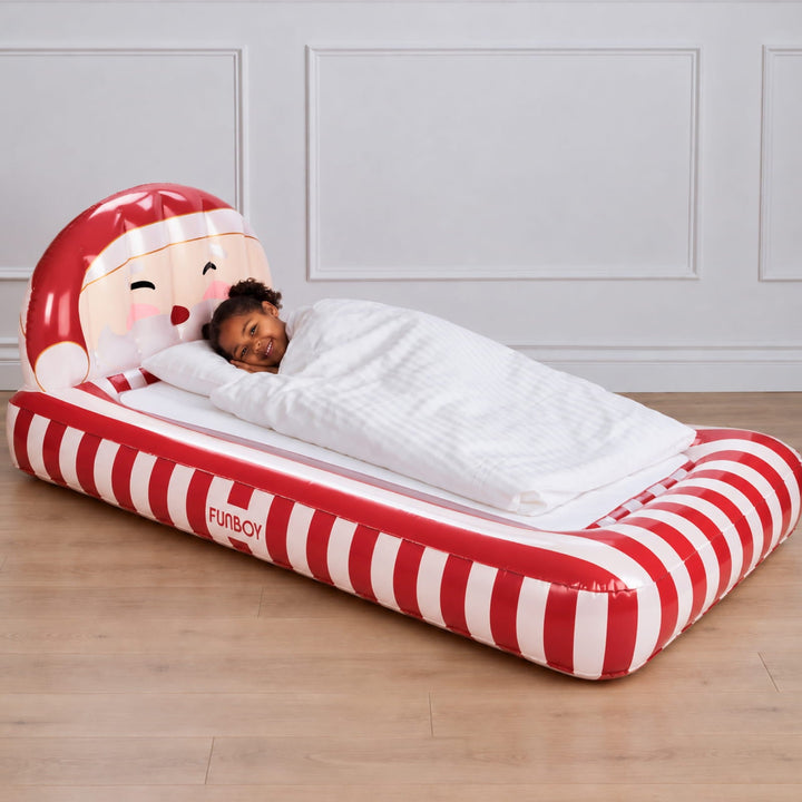 Child asleep in a Santa kids air mattress with red and white candy stripes